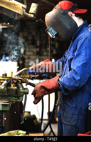 Schweißer ist Schweißen Metallteile in Garage. mit Schutzmaske, Industrie Stahl Schweißer Stockfoto