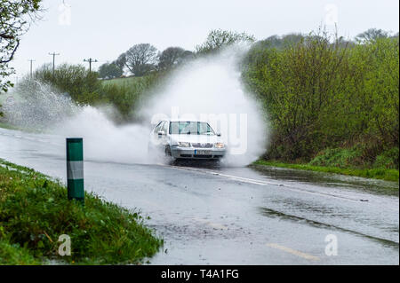 Skibbereen, West Cork, Irland. 15 Apr, 2019. Viel in Irland befindet sich mitten in einem Status Orange Niederschlag Warnung, ausgestellt von Met Éireann. Ein Auto Rennen durch einen Punkt Flut auf der N71 in der Nähe von Skibbereen. Credit: Andy Gibson/Alamy leben Nachrichten Stockfoto