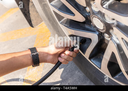 Ein Mann prüft die Reifen Luftdruck und füllen die Luft in einem Autoreifen. Stockfoto