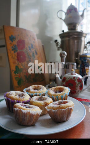 Hausgemachte süße Muffins in der Nähe von Malte Teekannen und Samowar auf dem Tisch Stockfoto