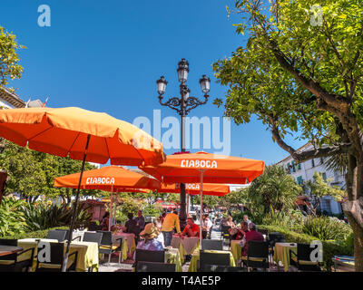 Marbella Orange Square Essen im Freien unter Sonnenschirmen - Plaza de los Naranjos, Speisen im Freien, Menschen, die Essen & Trinken in der Altstadt von Marbella Spanien genießen Stockfoto