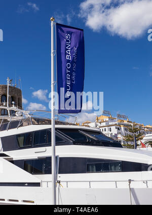 Puerto Banus Fahne Flagge im Wind flattern die Förderung der luxuriöse Yachthafen und Super Yachten von Puerto Banus, Marbella, Andalusien, Costa del Sol, Spanien Stockfoto