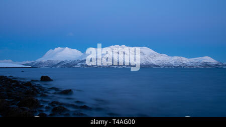 Blick von der Küstenlinie von Bakkejord, in der Nähe von Tromsø, Norwegen, Berge in der Ferne. März 2019. Stockfoto