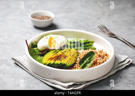 Gesundes Frühstück. Quinoa mit Ei, Gemüse in eine weiße Platte auf grauem Hintergrund Stockfoto