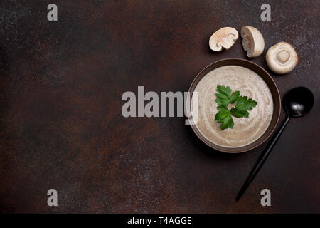 Pilz Suppe in eine braune Schale, Champignons auf braunem Hintergrund. Blick von oben. Kopieren Sie Platz Stockfoto