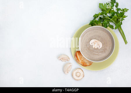 Pilzsuppe in Weiß Schüssel, Champignons, frische Petersilie auf weißem Hintergrund. Blick von oben. Kopieren Sie Platz Stockfoto