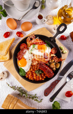 Englisches Frühstück serviert im Kochen Pfanne mit Spiegelei, Würstchen, Speck, Bohnen und Toast Stockfoto