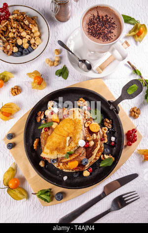 Flach der Pfannkuchen mit Beeren, Nüsse und Schokolade Soße zum Frühstück serviert. Stockfoto