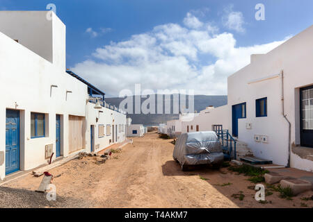Leere Straße mit Sand und weißen Häusern und ein Auto mit Kunststoff in Caleta de Sebo auf der Insel La Graciosa Lanzarote Stockfoto