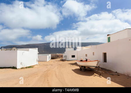 Leere Straße mit Sand und weißen Häusern und einem Trailer mit Boot in Caleta de Sebo auf der Insel La Graciosa Lanzarote Stockfoto