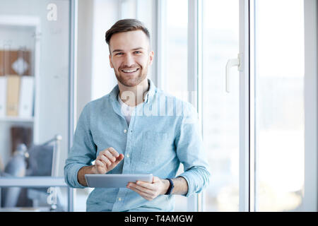 Junge Geschäftsmann posiert von Fenster Stockfoto