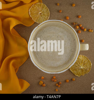 Eine Tasse Kaffee in einem gemütlichen Stil auf einem Kork und eine orange Stoff. Scheiben getrocknete Orangen- und Meer - buckthorns. Flach. Stockfoto