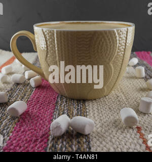 Eine Tasse Kaffee in einem gemütlichen Stil auf einem gestreiften Stoff Hintergrund mit Marshmallows. Stockfoto
