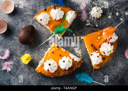 Hohen winkel Blick auf einige Stücke von Mona de Pascua, ein Kuchen in Spanien am Ostermontag gegessen, mit einem Schokoladen-ei, einem Teddy Küken und Federn o Stockfoto
