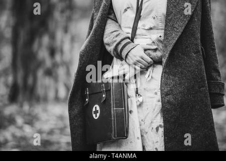 Re-Enactor trägt Historische deutsche Krankenschwester Sanitäter des Zweiten Weltkriegs Uniform mit Erste Hilfe Kit. Foto in den Farben Schwarz und Weiß. WWII WW2. Stockfoto