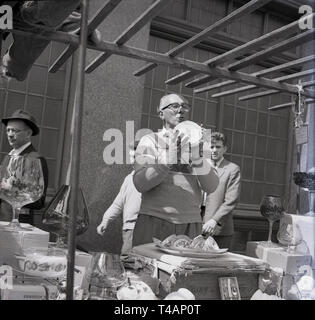 1960, historische, männliche Straßenhändler an seinem Open-air outdoor Stall, Verkauf Haushalt Porzellan- und Glaswaren, Stepney Markt, East London, London, England, Großbritannien Stockfoto