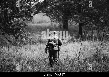 Single Re-Enactor als Deutsche Wehrmacht Infanterie Soldat im Zweiten Weltkrieg auf Patrouille durch Herbst Wald gekleidet. WWII WW 2 Mal. Foto in Schwarz Stockfoto