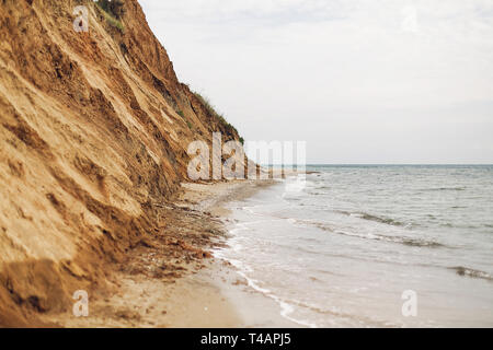 Wunderschöne Aussicht auf sandigen Felsen in der Nähe Meer Strand. Landschaft von Felsen am Strand und Wellen. Sommer Urlaub Konzept. Erkunden Sie interessante Orte Stockfoto