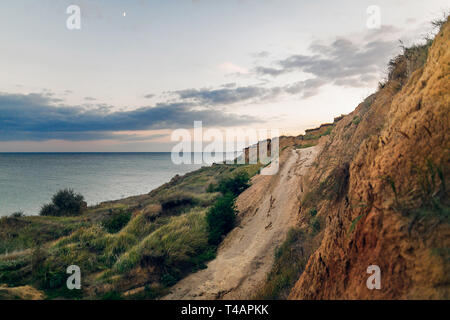 Wunderschöne Aussicht auf sandigen Felsen in der Nähe Meer Strand im Sonnenuntergang. Landschaft von Felsen am Strand und Wellen und bewölkter Himmel bei Sonnenuntergang und Sonnenaufgang. Sommer Urlaub anhand von quantitativen Simulatio Stockfoto