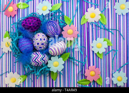 Ostern Hintergrund, Frühling Blumen, Ostereier, Ostern Eier mit einem filzstift eingerichtet, eine ultra-violett gestreiften Hintergrund Stockfoto