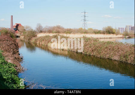 Coppermill Stream auf Walthamstow Feuchtgebiete, North East London UK, mit dem viktorianischen Motor Haus und Kamin im Hintergrund Stockfoto