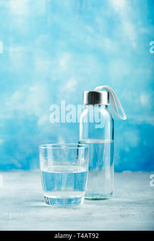 Glas Wasser mit einer Flasche am Tisch Stockfoto