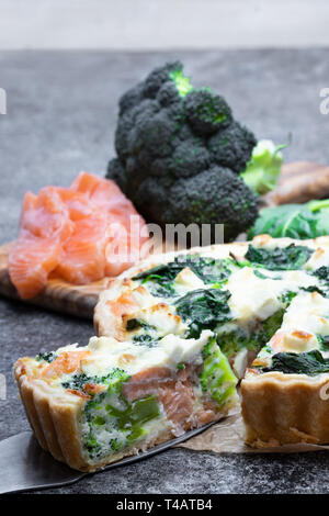 Roher Lachs Quiche, Brokkoli und Spinat auf Graue Tabelle Stockfoto