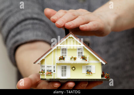 Hände halten ein Haus Stockfoto