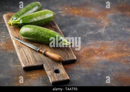 Drei frische Zucchini Squash auf einem hölzernen Schneidebrett Stockfoto