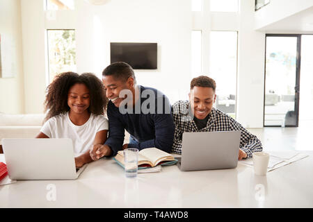 Lächelnd dad seiner jugendlich Kind Hilfe bei den Hausaufgaben, Vorderansicht, in der Nähe Stockfoto