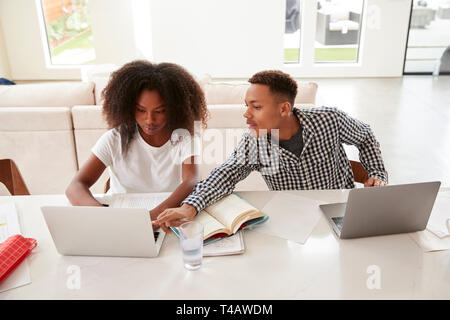 Teenager seine jüngere Schwester helfen mit ihren Hausaufgaben, beide mit Laptops, Erhöhte Ansicht Stockfoto