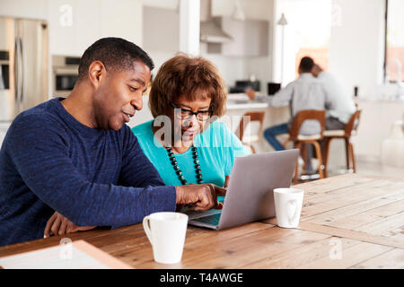 Im mittleren Alter schwarzer Mann helfen, seine Mutter einen Laptop Computer zu Hause verwenden, in der Nähe Stockfoto