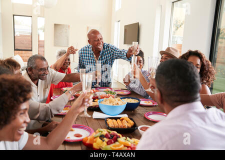 Großvater einen Toast stehend am Tisch feiern mit seiner Familie in der Nähe Stockfoto