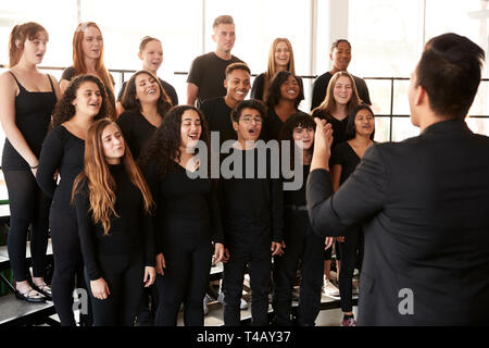 Männliche und weibliche Schüler singen im Chor mit Lehrer an der Schule für darstellende Kunst Stockfoto