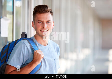Portrait von lächelnden männliche Studenten mit Rucksack im Korridor der Hochschule Gebäude Stockfoto
