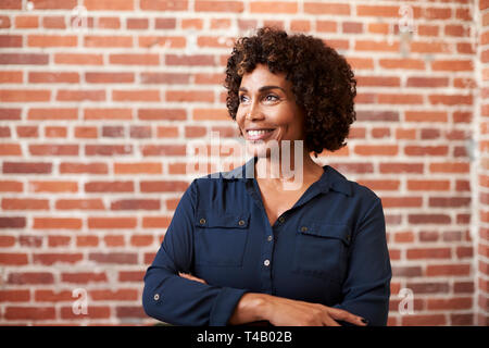 Lächelnd Reife Geschäftsfrau gegen Mauer stehend in modernen Büro Stockfoto