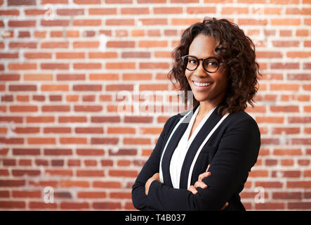 Portrait von lächelnden Geschäftsfrau Brille gegen Mauer stehend in modernen Büro Stockfoto