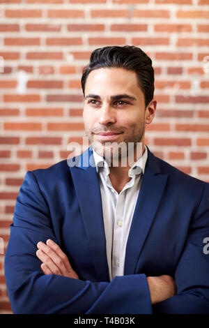 Lächelnd Reife Geschäftsmann gegen Mauer stehend in modernen Büro Stockfoto