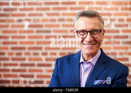 Portrait von lächelnden Reife Geschäftsmann Stehend gegen Mauer in modernen Büro Stockfoto