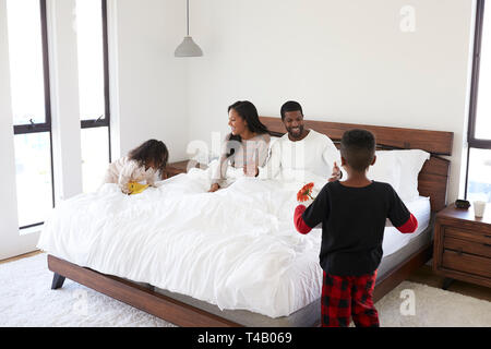 Kinder, die ihre Eltern ein Frühstück im Bett zu feiern Muttertag Vatertag oder Geburtstag Stockfoto