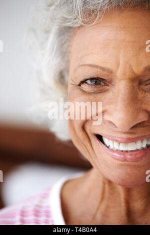 7/8 Kopf und Schultern Portrait von lächelnden älteren Frau sitzt auf dem Bett zu Hause Positive Suchen Stockfoto