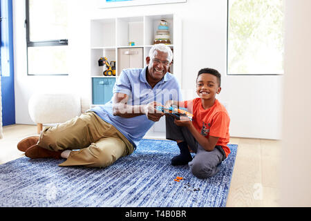 Portrait von Großvater mit Enkel liegen auf Teppich zu Hause Gebäude Robotic Modell zusammen Stockfoto