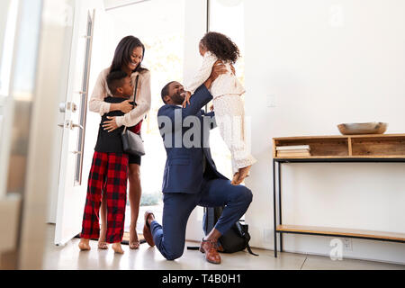 Kinder Gruß und Umarmen arbeiten Eltern, als sie von der Arbeit nach Hause zurückzukehren Stockfoto