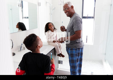 Großvater in Bad tragen Schlafanzug Zähneputzen mit Enkeln Stockfoto