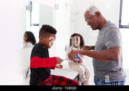Großvater in Bad tragen Schlafanzug helfen Enkelkinder Bürste Zähne Stockfoto