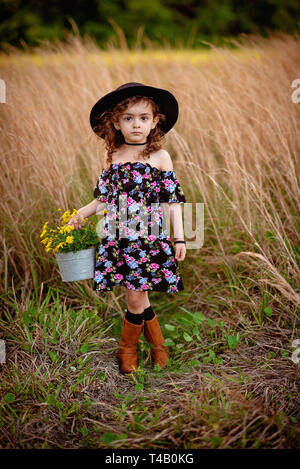 Junge Mädchen in Hut und Stiefel im hohen Gras Feld Stockfoto