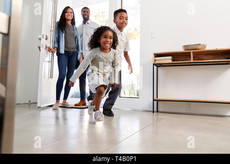 Eltern und Kinder nach Hause Öffnen der vorderen Tür und Innen läuft Stockfoto