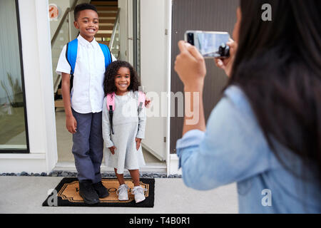 Mutter unter Foto von Kindern mit Handy am ersten Tag wieder in der Schule Stockfoto