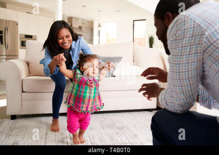 Familie zu Hause Förderung Baby Tochter Erste Schritte Stockfoto