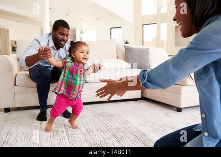 Familie zu Hause Förderung Baby Tochter Erste Schritte Stockfoto